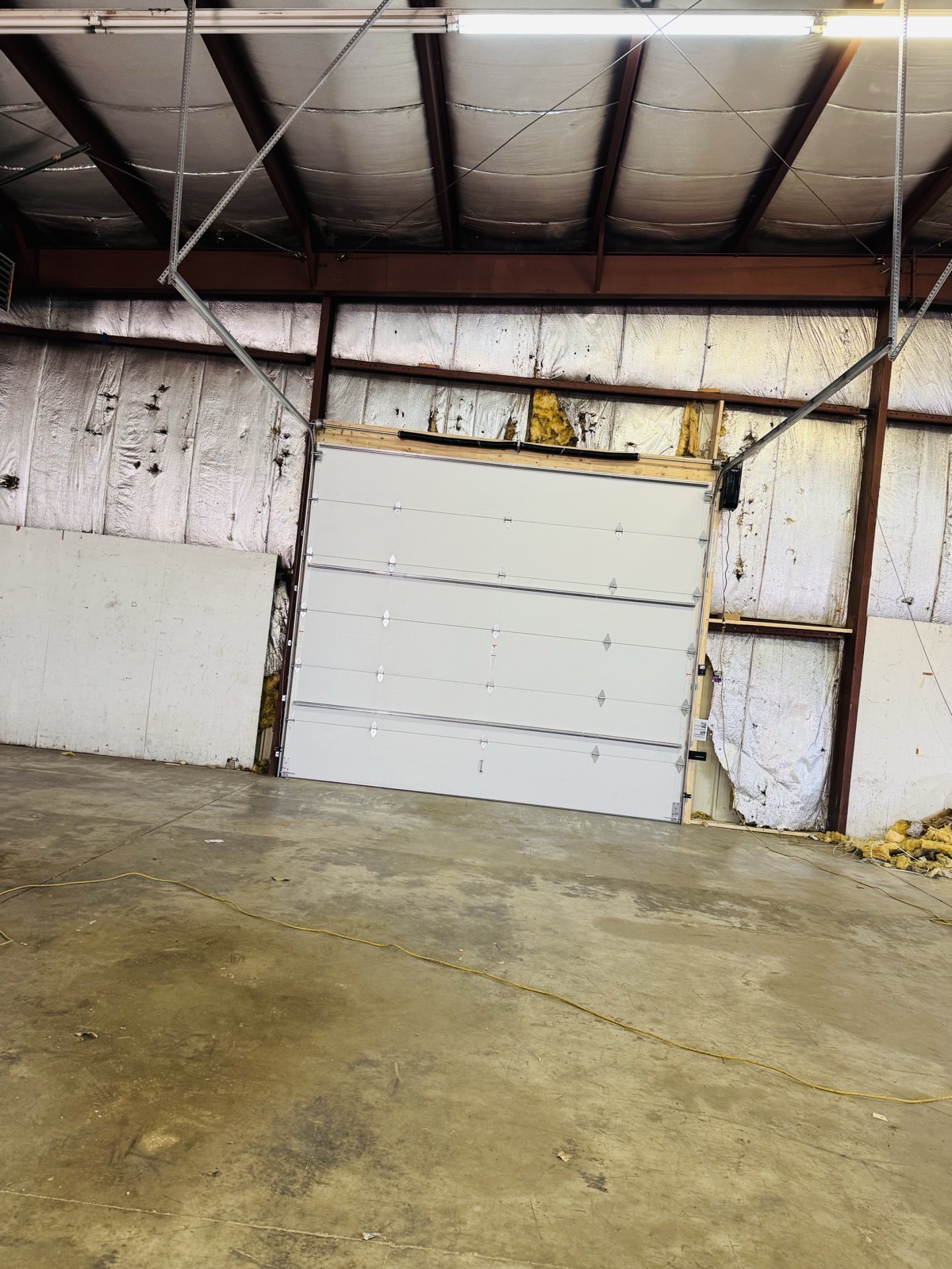 Large commercial garage door installed inside a metal warehouse building