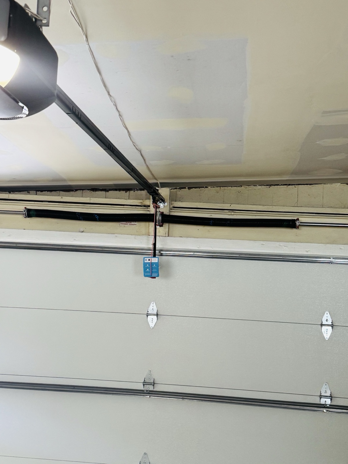 Close-up of a torsion spring and safety cable assembly above a garage door