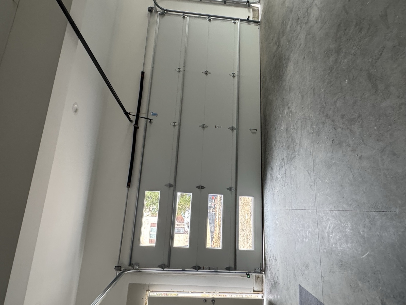 Newly installed garage door with window inserts, viewed from inside a finished garage